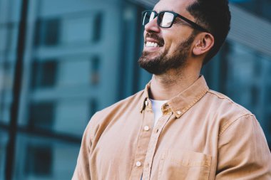 Dijital teknolojinin neşeli kullanıcıları ellerinde cep telefonu ve gülümsemeyle şehir ortamında duruyorlar.