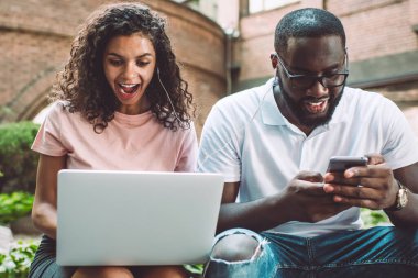 Şaşırmış hippi kız, favori web mağazasında indirimli indirimli alışveriş kuponuyla birlikte Afro-Amerikalı erkek arkadaşıyla şehir ortamında zaman geçirmesine şaşırmış.