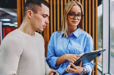 Gözlüklü nitelikli bayan öğretmen, çalışmalara işaret ediyor ve bunu yetenekli bir öğrenci olarak gösteriyor. Modern ofiste çalışma planını tartışan iki profesyonel erkek ve kadın tasarımcı.