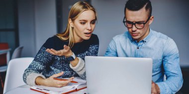 Kablosuz internet kullanarak internet sitesini tartışan iki zeki öğrenci. Bilgisayarda özel ders izleyen genç erkek ve kadın web mağazası geliştirme fikirleri hakkında konuşuyorlar.