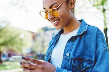 Güneş gözlüklü neşeli hippi kız sosyal ağlarda takipçilerle sohbet ediyor kablosuz internetle bağlantılı, web sitesinden yorum okuyan mutlu kadın blogcu.