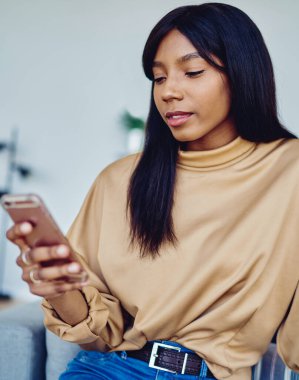 Oldukça koyu tenli bin yıllık bir kadın evde otururken online rezervasyon için akıllı telefon uygulaması kullanıyor, genç Afrikalı Amerikalı hippi kız cep telefonundan gelen uyarıyı okudu.