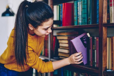 Üniversite kütüphanesinde edebiyat ve eğitim arayan beyaz kadın öğrenci, kitapçıdaki raflardan kitap seçen ilginç roman arayan pozitif hippi kız.