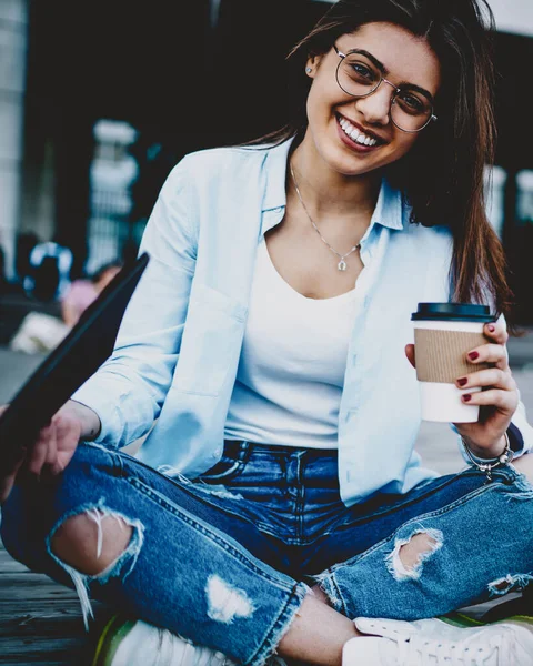 在城市里 穿着时髦眼镜 手握美味咖啡 悠闲自在地对着相机微笑的迷人的年轻女子的画像 — 图库照片