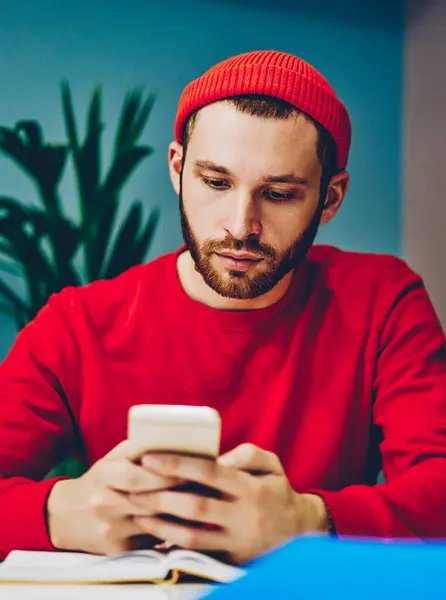 사무실에 앉아있는 스마트 폰에서 메일을 모자에 심각한 펜시브 밀레니엄 전화에 — 스톡 사진