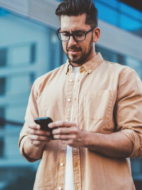 30 'lu yaşlarda beyaz bir adam şehir ortamında dikilirken iş arkadaşlarıyla sohbet ediyor. Normal gömlekli yakışıklı bir erkek, cep telefonundan 4G' ye bağlanan bir uyarı mesajı veriyor.