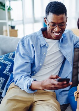 Neşeli Afro-Amerikan erkek ve kadın hipsterler birbirleriyle konuşuyorlardı. Yeni akıllı telefon uygulaması kullanıyorlardı. 4G 'ye bağlıydılar.