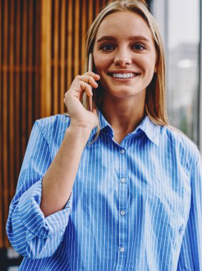 Sıradan giyinmiş güzel bir genç kadının portresi kameraya gülümserken akıllı telefondan arıyor ve cep telefonu operatörüyle konuşuyor. Güzel hipster öğrenci cep telefonuyla iletişim kuruyor.