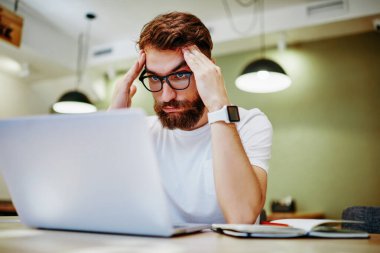 Vadesi dolmadan önce laptop 'da fazla mesai yapan, vizyon koruması için göz takan üzgün erkek serbest yazar, internet sitesindeki internet projesi ile ilgili sorunlar yüzünden başı ağrıyan yorgun hippi.
