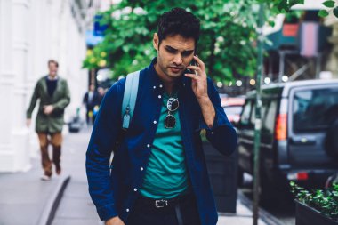 Mavi sırt çantalı yakışıklı sıradan bir adam sokakta yürüyor ve New York 'ta cep telefonuyla konuşuyor.