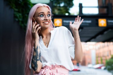 Uzun gül saçlı, şık yaz kıyafetleri giyen, moda gözlüklü, cep telefonu konuşmaları sırasında sürpriz ifadeler takınan genç ve çekici bir kadın. 