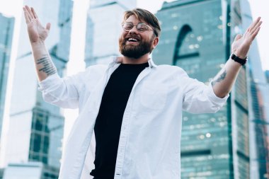 Moda optik gözlüklü neşeli beyaz erkek portresi kameraya gülümseyen ve mutlu hippi adam sevinçten havalara uçarken ellerini kaldıran gözler için koruma sağlıyor.