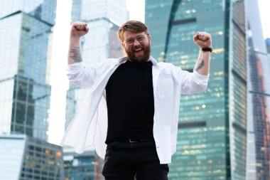 Metropolis 'i gezmeyi kutlayan şehir merkezinde kameraya gülümseyen, gökdelenlerin arkasında poz veren mutlu bir adamın uzun boylu bir portresi.