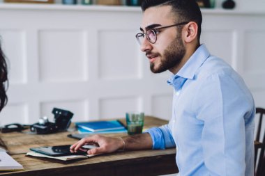 Gözlüklü, kendine güveni tam ve pozitif bir adam. Yeni iş projesinin detaylarını tartışan gündelik giysiler içindeki kadın girişimciyi dikkatle dinliyor.