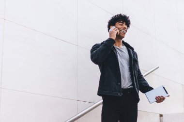 Modern stil güler yüzlü genç esmer Afrikalı Amerikalı adam telefonda konuşurken gündüz vakti şehir merdivenlerinde yürüyordu.