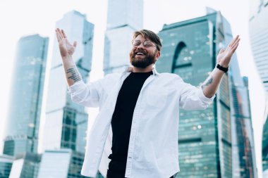 Moda optik gözlüklü neşeli beyaz erkek portresi kameraya gülümseyen ve mutlu hippi adam sevinçten havalara uçarken ellerini kaldıran gözler için koruma sağlıyor.