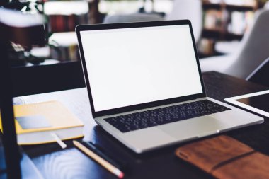 Boş beyaz ekran ve tabletle modern dizüstü bilgisayar siyah masa üzerine yerleştirilmiş ve tasarım iç mimarisi bulanık arka planda