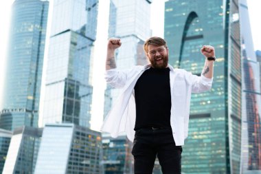 Metropolis 'i gezmeyi kutlayan şehir merkezinde kameraya gülümseyen, gökdelenlerin arkasında poz veren mutlu bir adamın uzun boylu bir portresi.