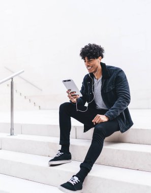 Gülümseyen erkek blogcu kulaklıkla komik film seyrediyor, hipster adam dijital tablet üzerinden olumlu arkadaşça video konuşması yapmak için şehir ortamında zaman harcıyor.