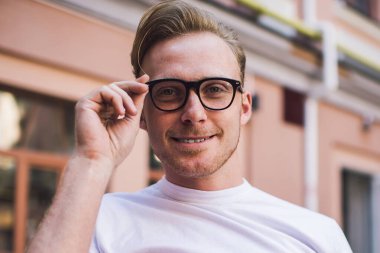 Neşeli, karizmatik genç adam arkadaşlarıyla sohbet ediyor. Boş vakitlerini telefon takıp, bardakları ayarlıyor ve yaz kafesinde kameraya bakıyor.