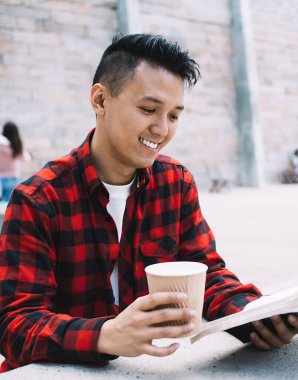 Asyalı hevesli, neşeli ve kahveli adam üniversite derslerinden sonra şehir merkezinde dinlenirken kitap okumaktan esinlenerek uzaklaştı.