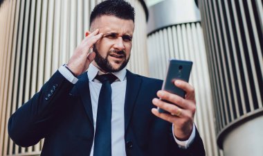 Modern şehrin merkezinde caddede dikilirken, takım elbiseli, kaşlarını çatan ve akıllı telefonları karıştıran...