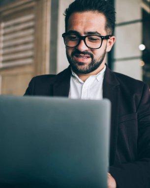 Görme düzeltmesi için gözlüklü beyaz erkek girişimci çevrimiçi proje gelirinden memnun, dizüstü bilgisayardan haberleri okuyor, resmi olarak zengin erkek ekonomist posta kontrolü yapıyor