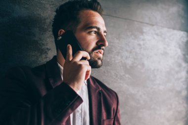 Zarif takım elbiseli ciddi bir genç, akıllı telefon kullanıyor. İş arkadaşıyla konuşuyor. Proje saatlerini iş yerinde geçirip gözlerini kaçırıyor.