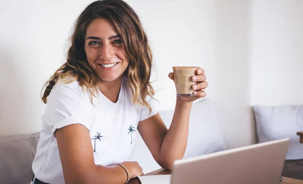 ラップトップや紙でカフェに座っている間 幸せな現代の女性のフリーランサーは一時停止し コーヒーのカップを楽しんで — ストック写真
