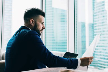 İşletme tarzı giysiler içinde modern binalarla birlikte arka planda çalışan konsantre erkek ofis çalışanlarının yan görüntüsü