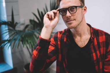 Kafeteryada dinlenip kameraya bakarak siyah gözlük takan sarı saçlı yakışıklı genç adamın portresi.