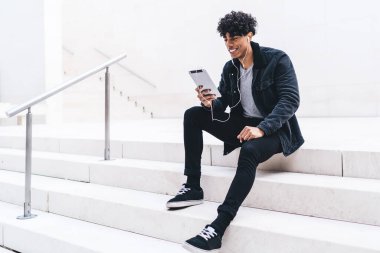 Gülümseyen erkek blogcu kulaklıkla komik film seyrediyor, hipster adam dijital tablet üzerinden olumlu arkadaşça video konuşması yapmak için şehir ortamında zaman harcıyor.