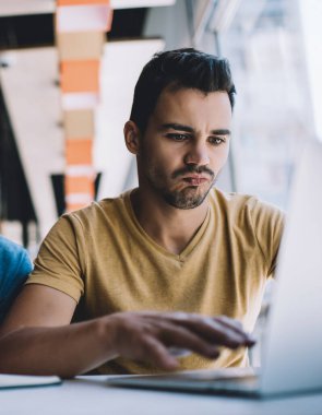 Laptop kullanan ve kahve içerken ve kafede otururken başlangıç projesi üzerinde çalışan konsantre erkek serbest çalışanlar.