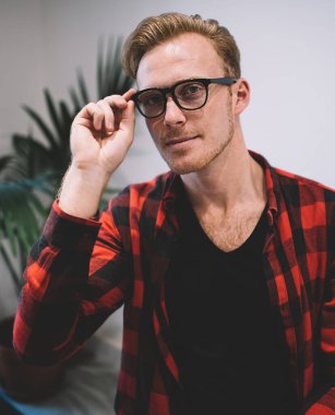 Kafeteryada dinlenip kameraya bakarak siyah gözlük takan sarı saçlı yakışıklı genç adamın portresi.