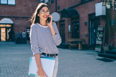 Gündelik giysiler içinde gülümseyen hippi kız üniversite sunumuna bilgi ekipmanlarıyla gidiyor ve gezici internet ve uygulama aracılığıyla cep telefonu sohbeti yapıyor, uluslararası çağrı kavramı