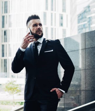 Adam, parlak güneş altında parlak binaları olan megapolis 'e karşı merdivenlerde dikilirken telefon ediyor ve başka tarafa bakıyor.