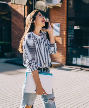 Klasik gözlüklü müreffeh hippi kız şehir ortamında yürüyor ve arkadaşlarıyla akıllı telefon iletişiminin tadını çıkarıyor açık havada dolaşarak iletişim kuruyor, gözlüklü mutlu bir milenyum kadını telefonla arıyor.