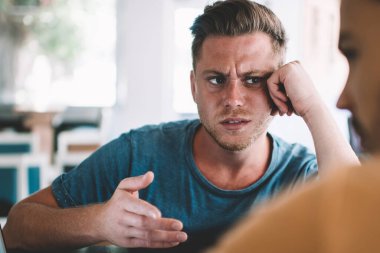 Gündelik giysilerle kaşlarını çatan serbest çalışan, ortakla birlikte kafede el ele oturarak kooperatif proje tartışması stratejisi oluşturan,