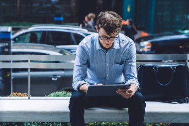 Gözlüklü yakışıklı genç adam cam duvara yansıyor Manhattan, New York 'ta sokakta tablet kullanıyor.