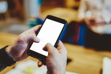 Kol saatleri ve dövme mesajları olan tanınmayan odaklı bir adam ofisteki meslektaşıyla aynı masada duruyor.