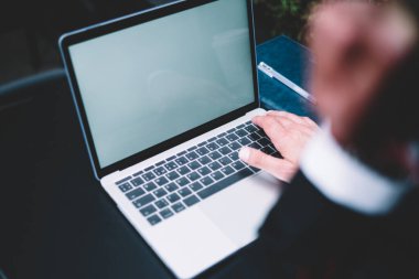 Masada defter ve kalemle yazı yazan koyu renk takım elbise uzmanının modern dizüstü bilgisayarından.