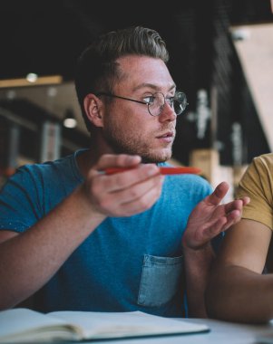 Modern kafede gayri resmi toplantı sırasında bilgisayarla oturup iş problemlerini tartışan rahat giyimli genç erkek iş arkadaşları hayal kırıklığına uğradı