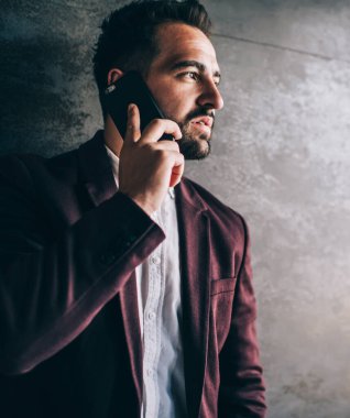 Zarif takım elbiseli ciddi bir genç, akıllı telefon kullanıyor. İş arkadaşıyla konuşuyor. Proje saatlerini iş yerinde geçirip gözlerini kaçırıyor.