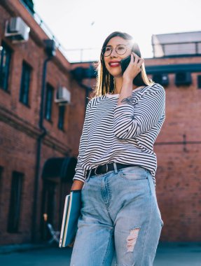 Gündelik giysiler içinde gülümseyen hippi kız üniversite sunumuna bilgi ekipmanlarıyla gidiyor ve gezici internet ve yeni başvuru yoluyla cep telefonu sohbeti yapıyor.