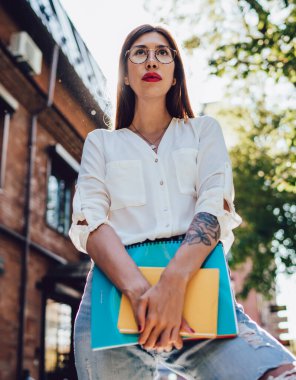 Eğitimi için ekipmanı olan zeki bir kadın dışarıda duruyor ve üniversite meslektaşını bekliyor, çekici İspanyol kadın gazeteci şehir sokaklarında öğrenmek için not defteri tutuyor.