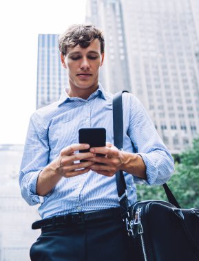 Şehir merkezindeki şehir merkezinde dikilirken modern cep telefonunda SMS okuyan ve iletişim için 4G kablosuz internet bağlantısı kullanan işverenin bakış açısının altında akıllı işadamı sohbeti