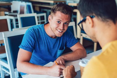 Günlük giysiler içinde neşeli bir serbest yazar. Not defterine not yazar. Kafedeki masada oturmuş kameraya bakan bir iş arkadaşıyla işe başlarken.