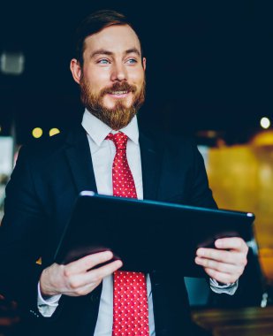 Gülümseyen kızıl sakallı iş adamı. Katı siyah takım elbise içinde. Kırmızı kravat.