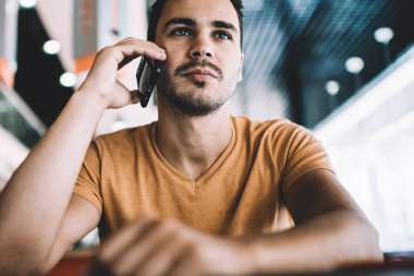 Serbest çalışmaya odaklanmış, günlük giysiler giyen, mobil dinleyici kullanan bir girişim yaratan, iş yerindeki çalışma masasında oturan iş arkadaşı tartışmasını dinleyen,