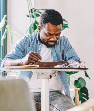 Ciddi daldırılmış zeki siyah adam masada sörf tableti ve içeriği dikkatle okumak iç mekandaki önemli proje üzerinde sıkı çalışma sırasında